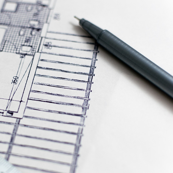 A pen on top of a piece of paper that has a floor plan sketched on it.