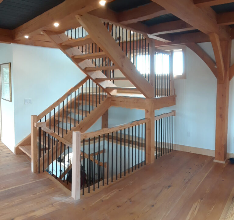 A wooden staircase is shown featuring contrasting black balusters.